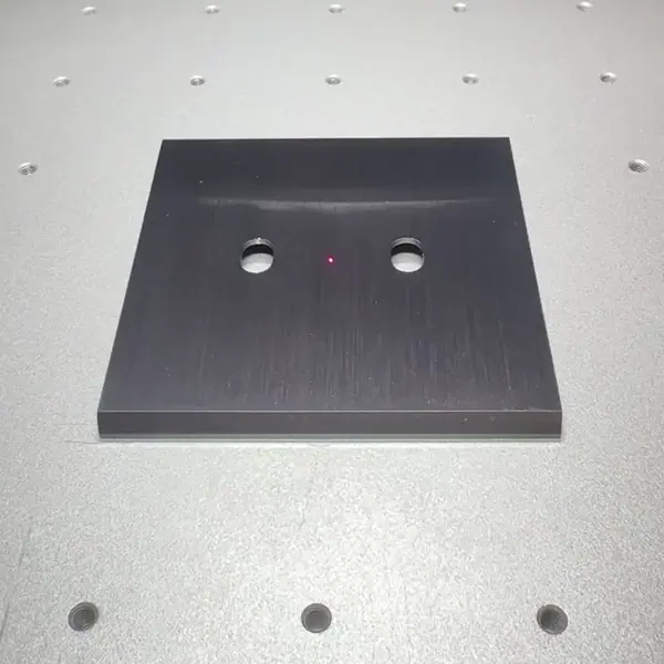 Le laser grave progressivement les pictogrammes, les textes et les lignes de montagne sur une plaque noire à l’atelier.