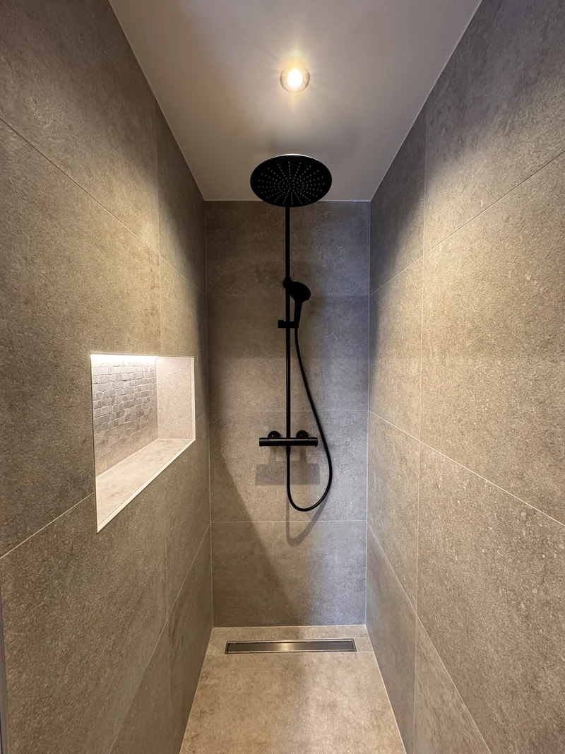 Douche avec éclairage au plafond et niche murale lumineuse.