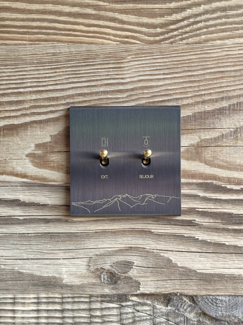 Lignes de montagne gravées sur une plaque noire à deux interrupteurs.