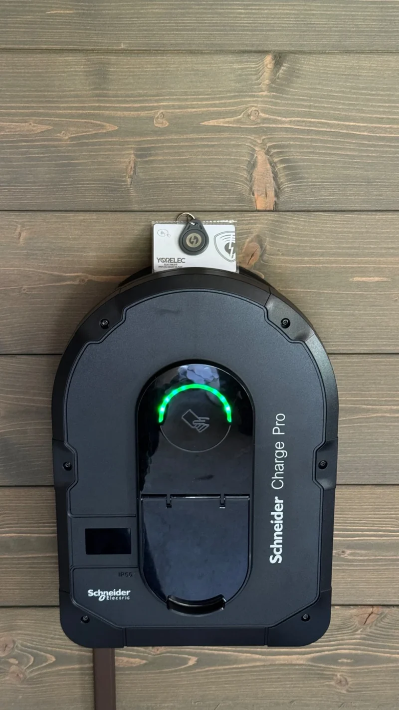 Borne Schneider Charge Pro installée sur un bardage bois, avec voyant de recharge vert.