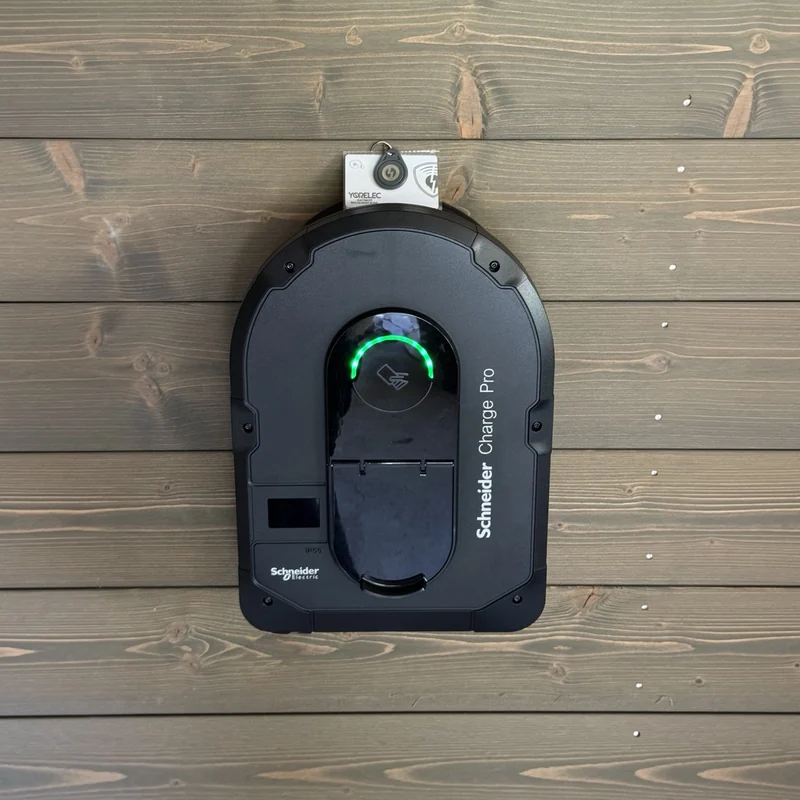 Borne Schneider Charge Pro vue de face sur un bardage bois, avec badge et porte-clés Yorelec.