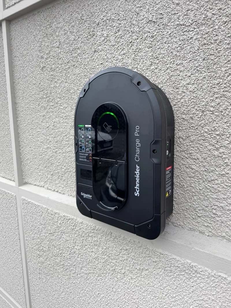Borne Schneider Charge Pro fixée sur une façade claire, avec voyant vert.