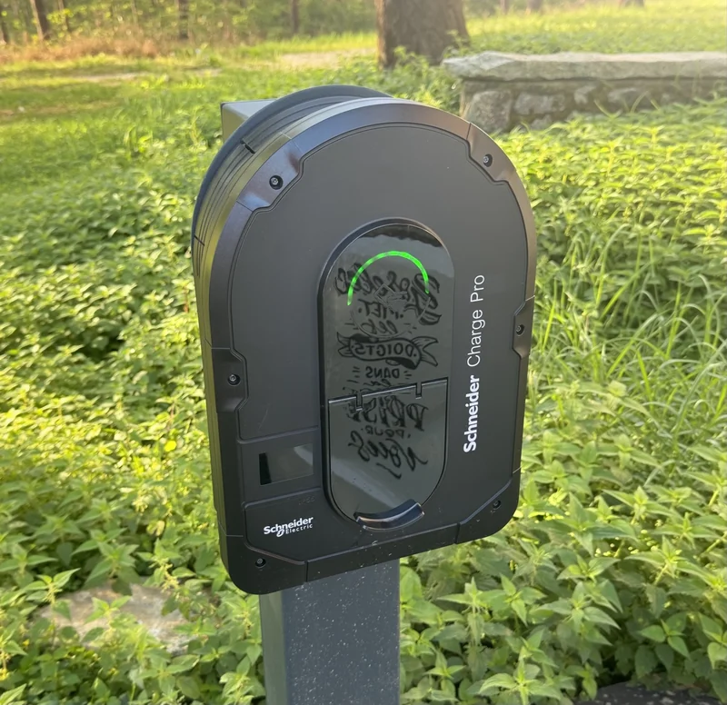 Borne Schneider Charge Pro sur pied au bord d’un espace végétalisé.