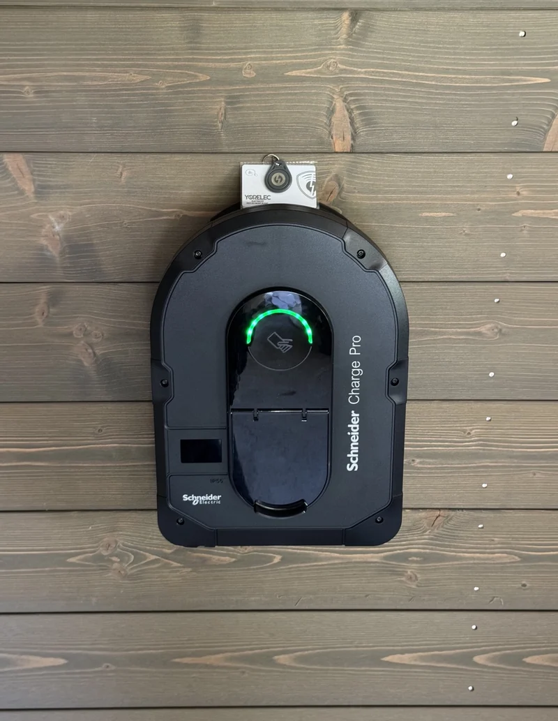 Borne Schneider Charge Pro vue de face sur un bardage bois, avec son voyant vert et ses badges Yorelec.