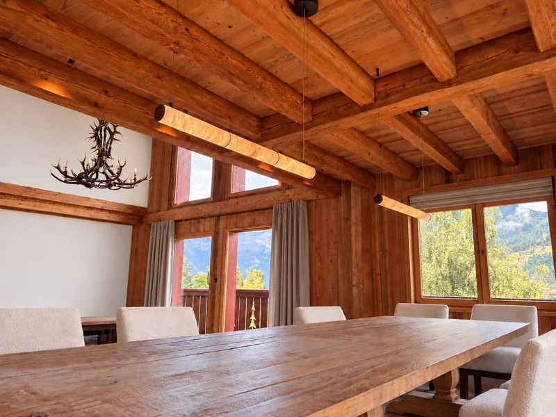 Suspensions au-dessus d’une table dans un chalet ouvert sur les montagnes.