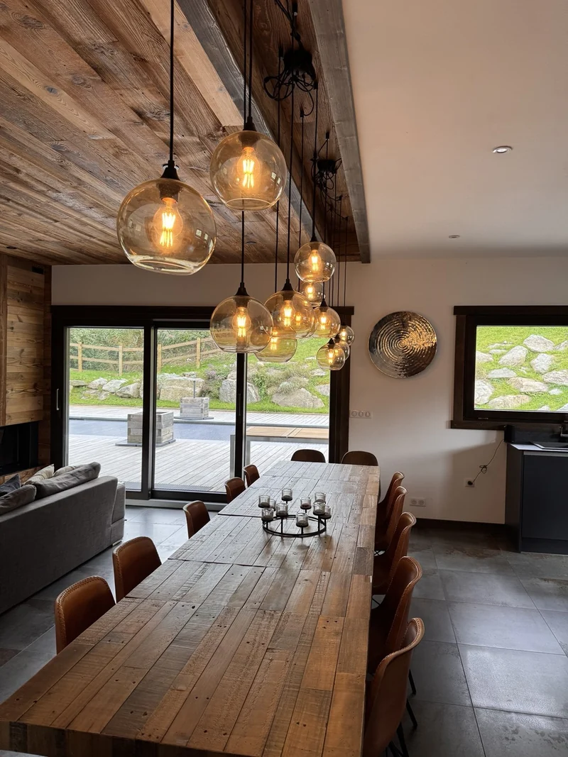 Alignement de suspensions en verre au-dessus d’une table en bois.